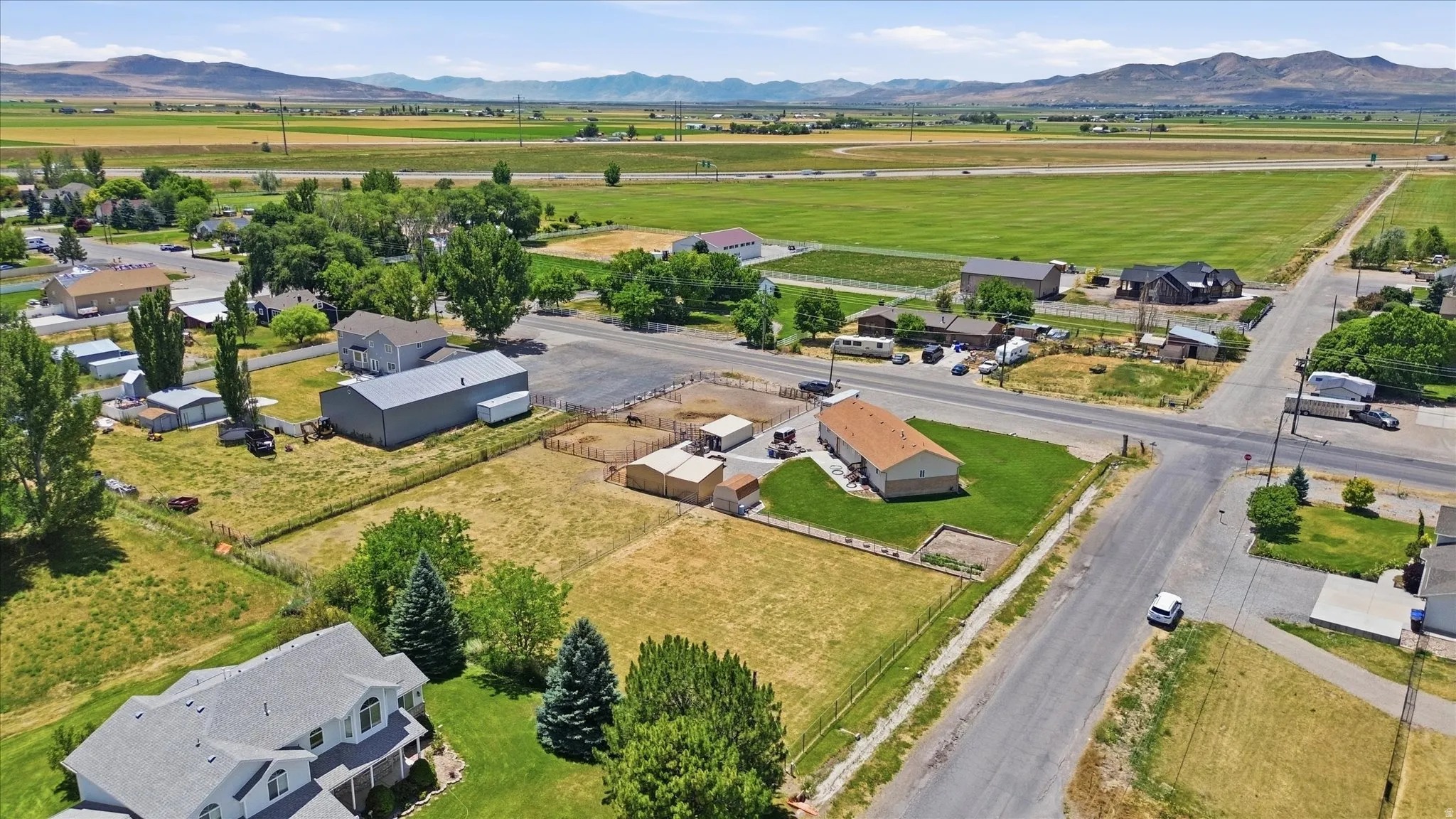 Expansive aerial perspective showcasing a rural property with surrounding fields and distant mountains