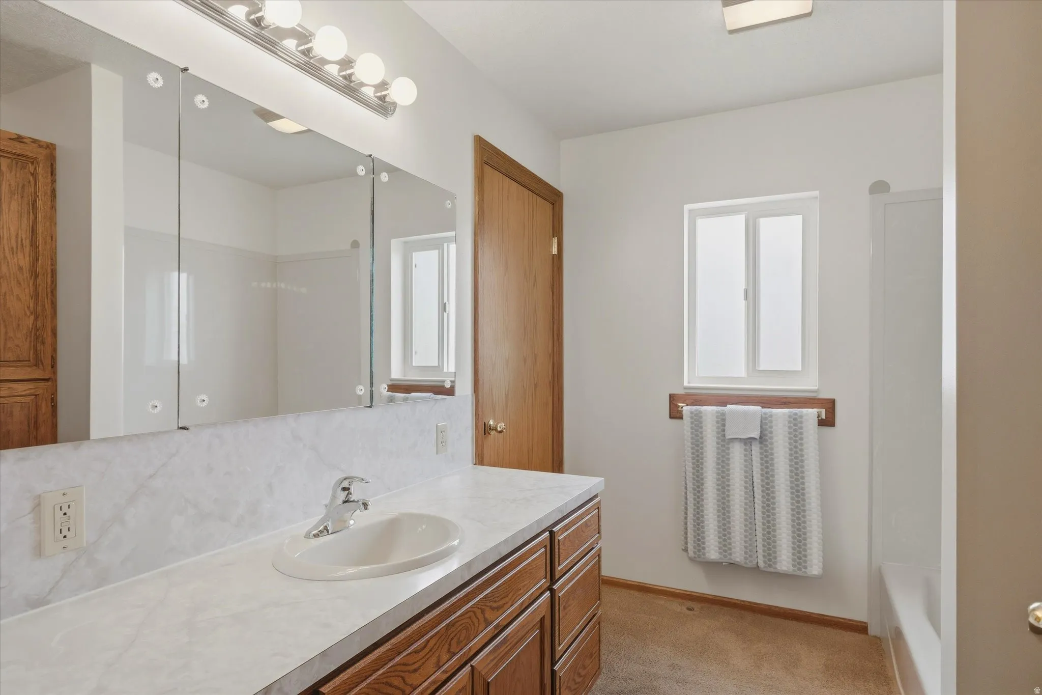 Bathroom featuring a wood-finish vanity with an integrated sink and laminate countertop