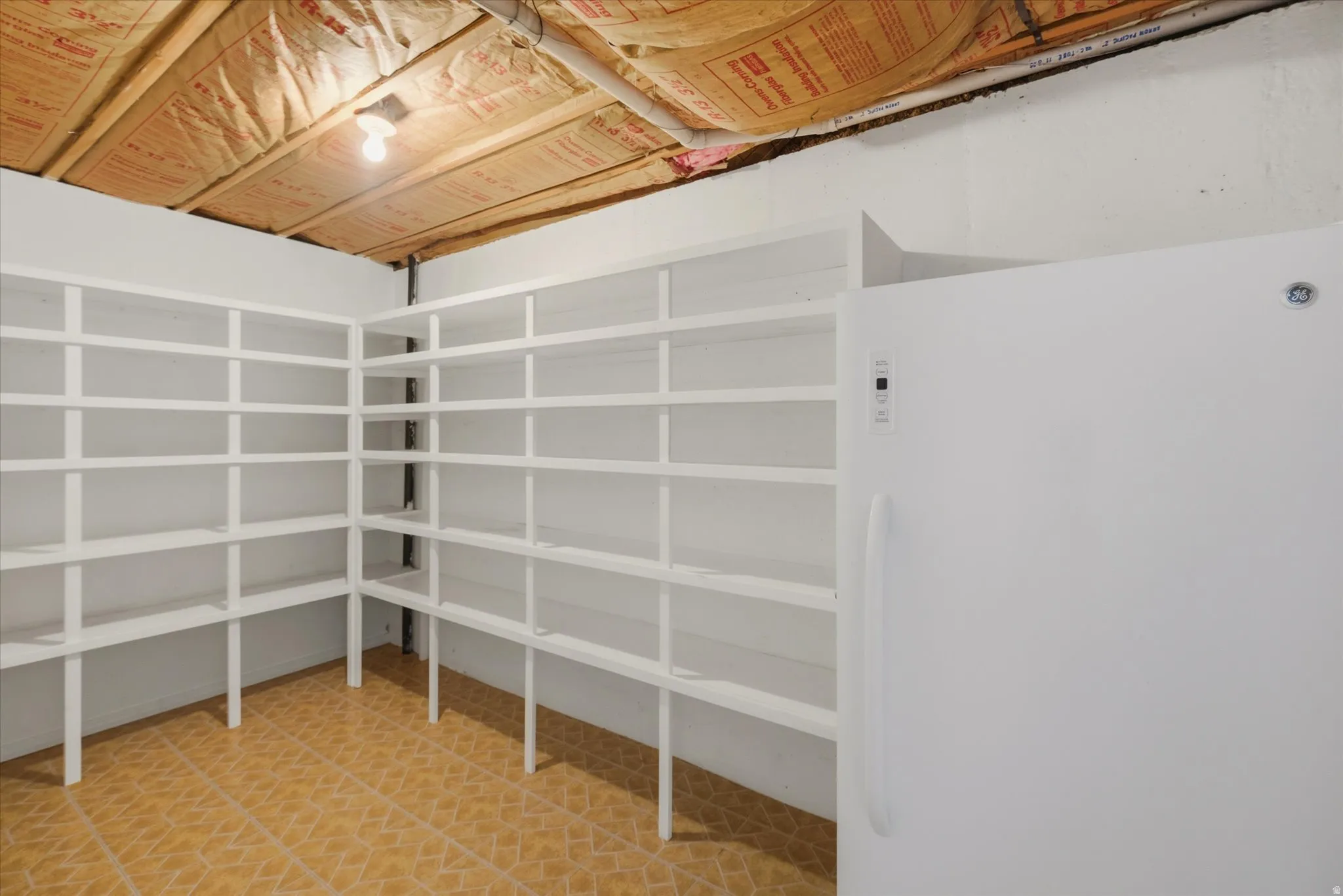 Corner storage shelving unit with multiple white shelves, a freestanding white refrigerator, and tile flooring