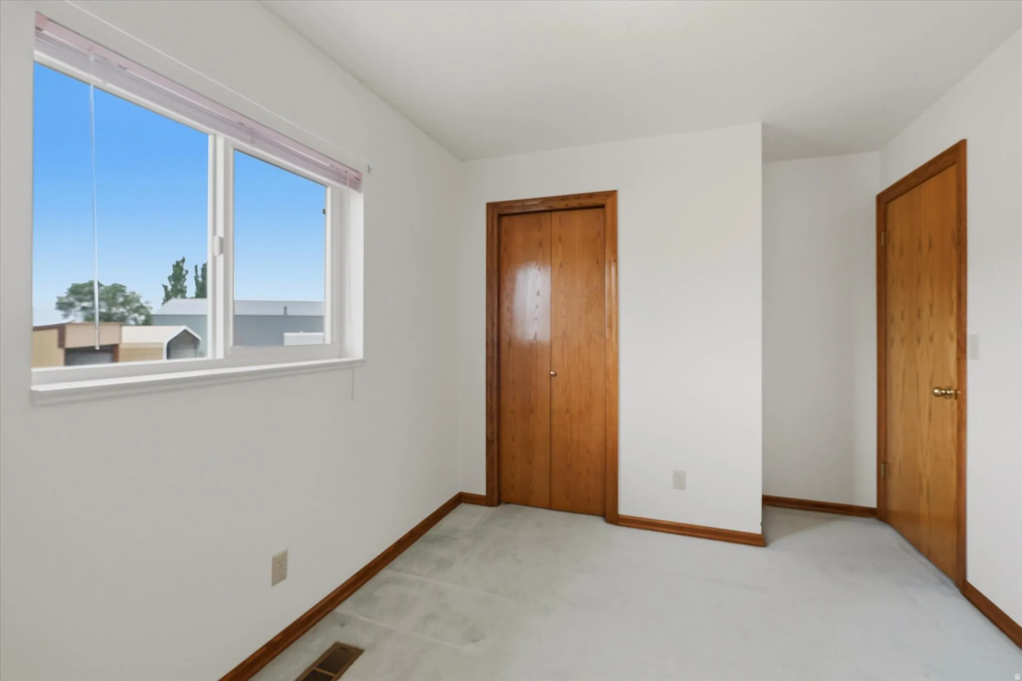 Bright interior space featuring a double-pane window, wood-finish doors, and white walls