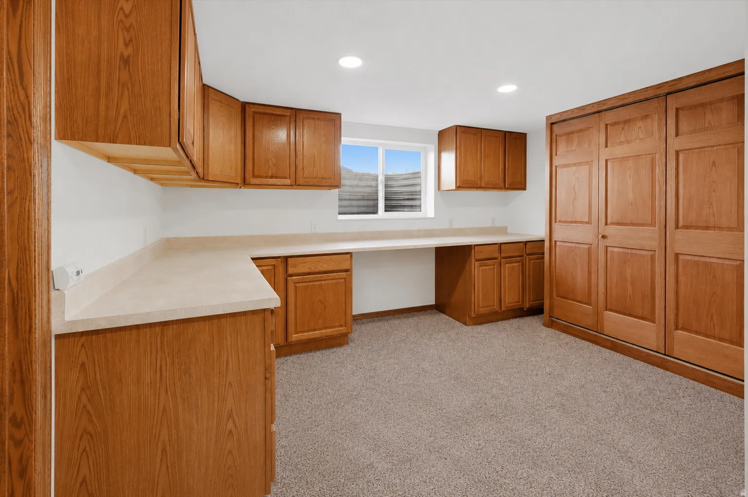 Built-in wood-finish cabinetry with extensive countertop space, recessed lighting, and a large window