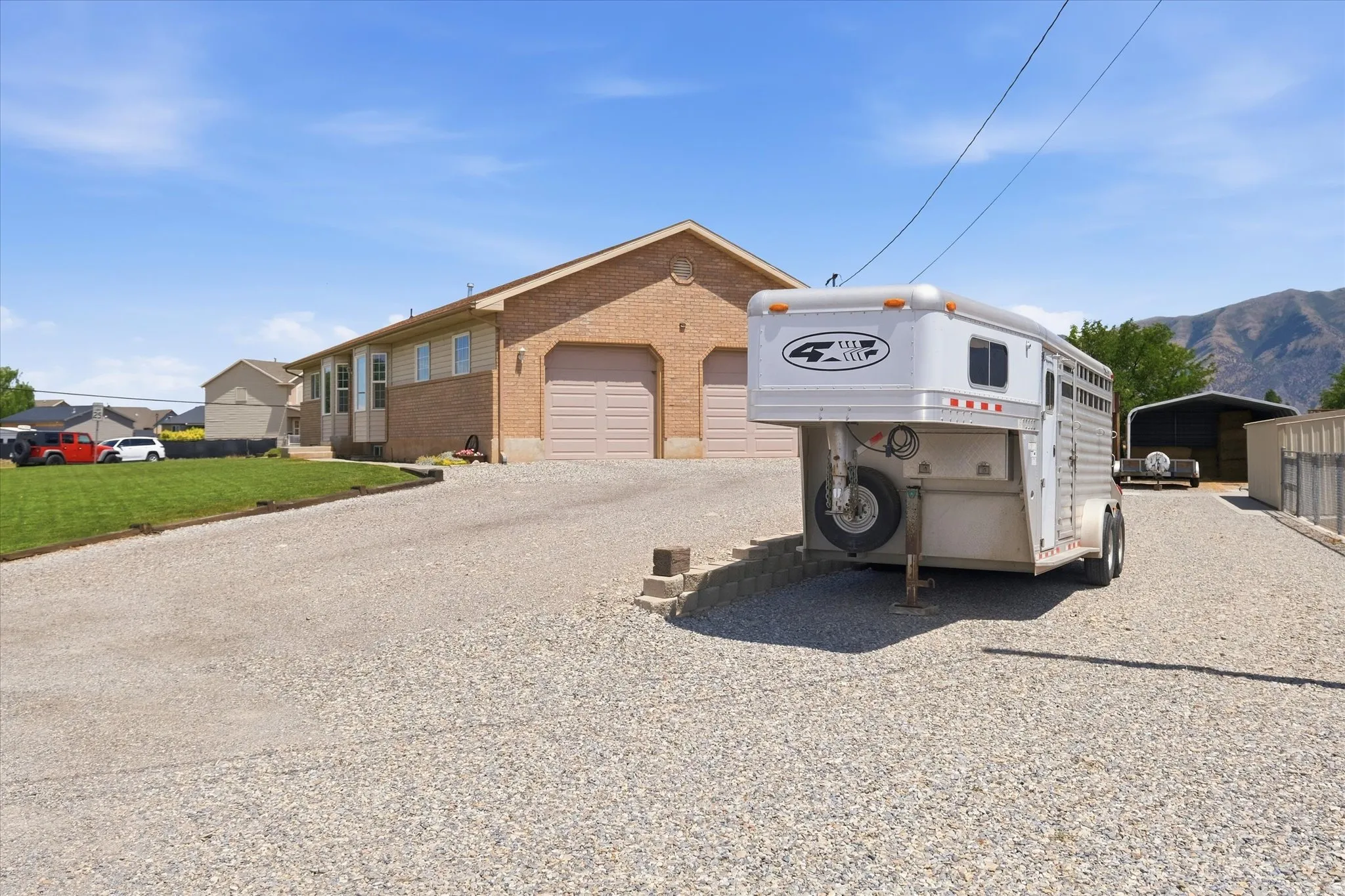 Brick-front property featuring two garage doors, a gravel driveway, and a partially sodded lawn