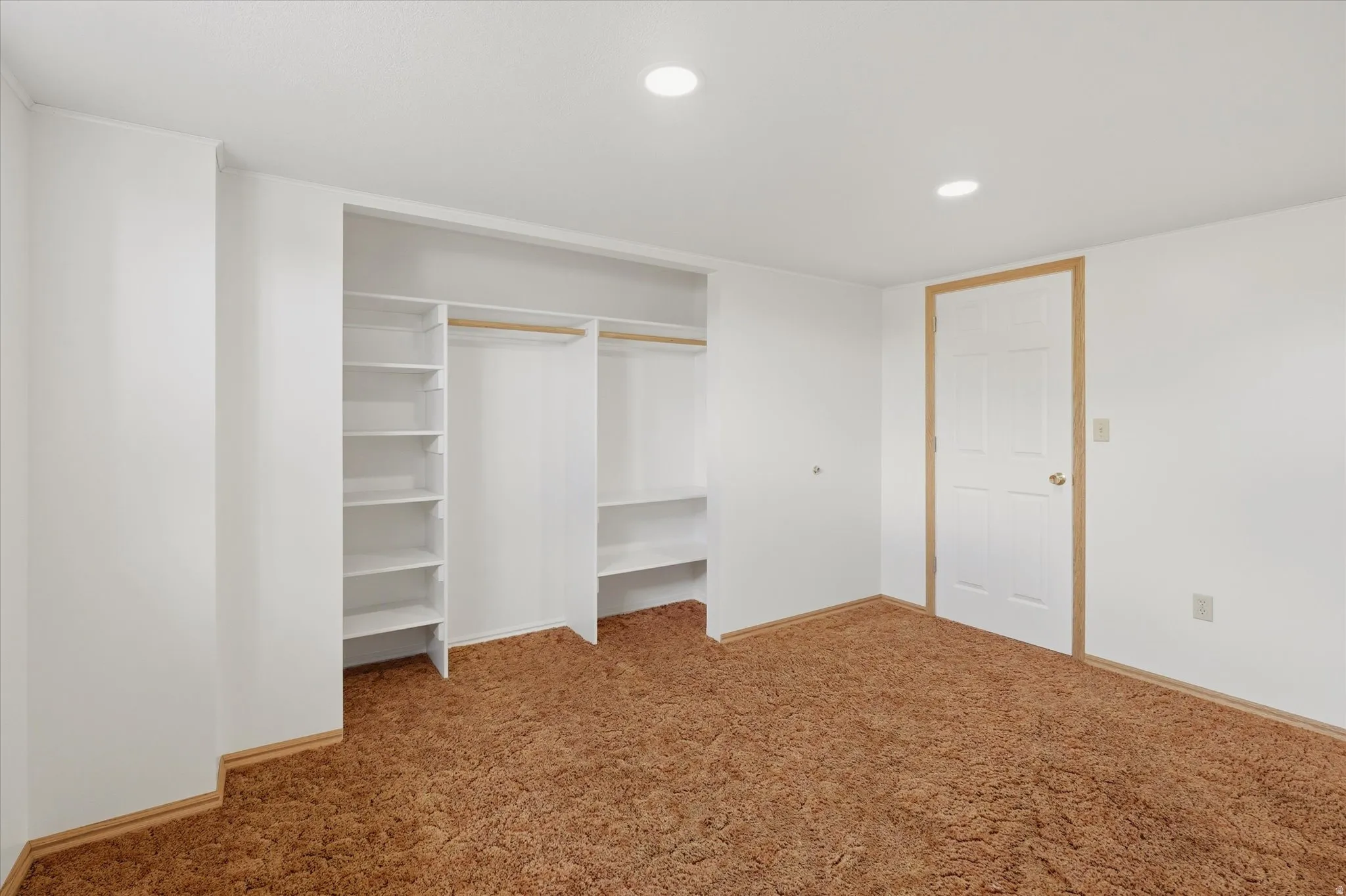 Expansive wall-to-wall carpeting complements bright white walls and recessed lighting