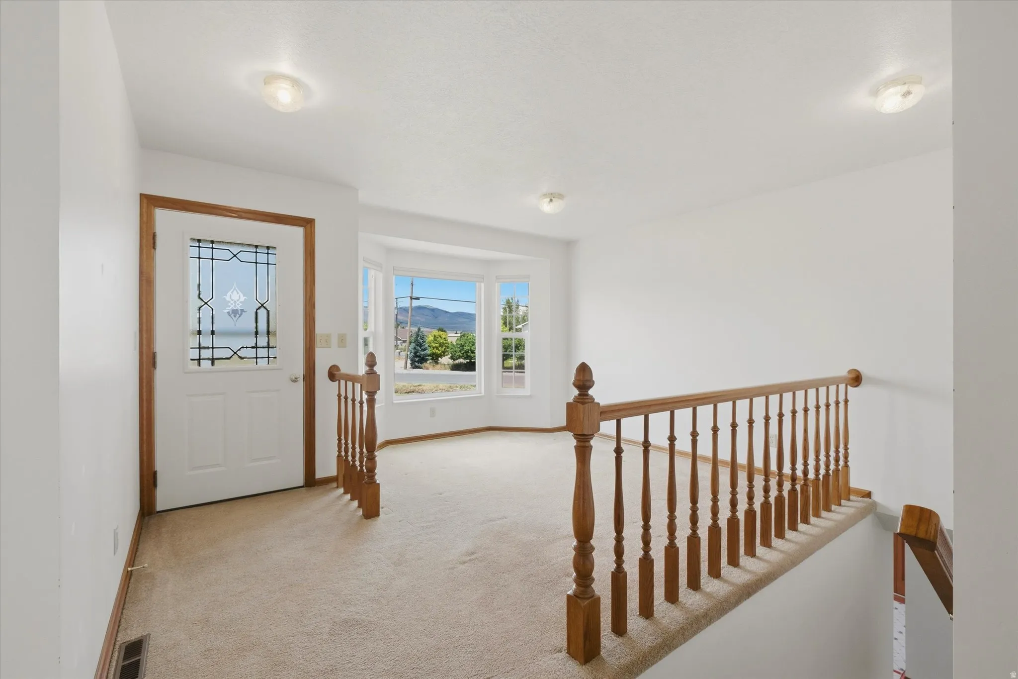 Entryway featuring a decorative glass panel door, light-toned carpeting, and a bay window