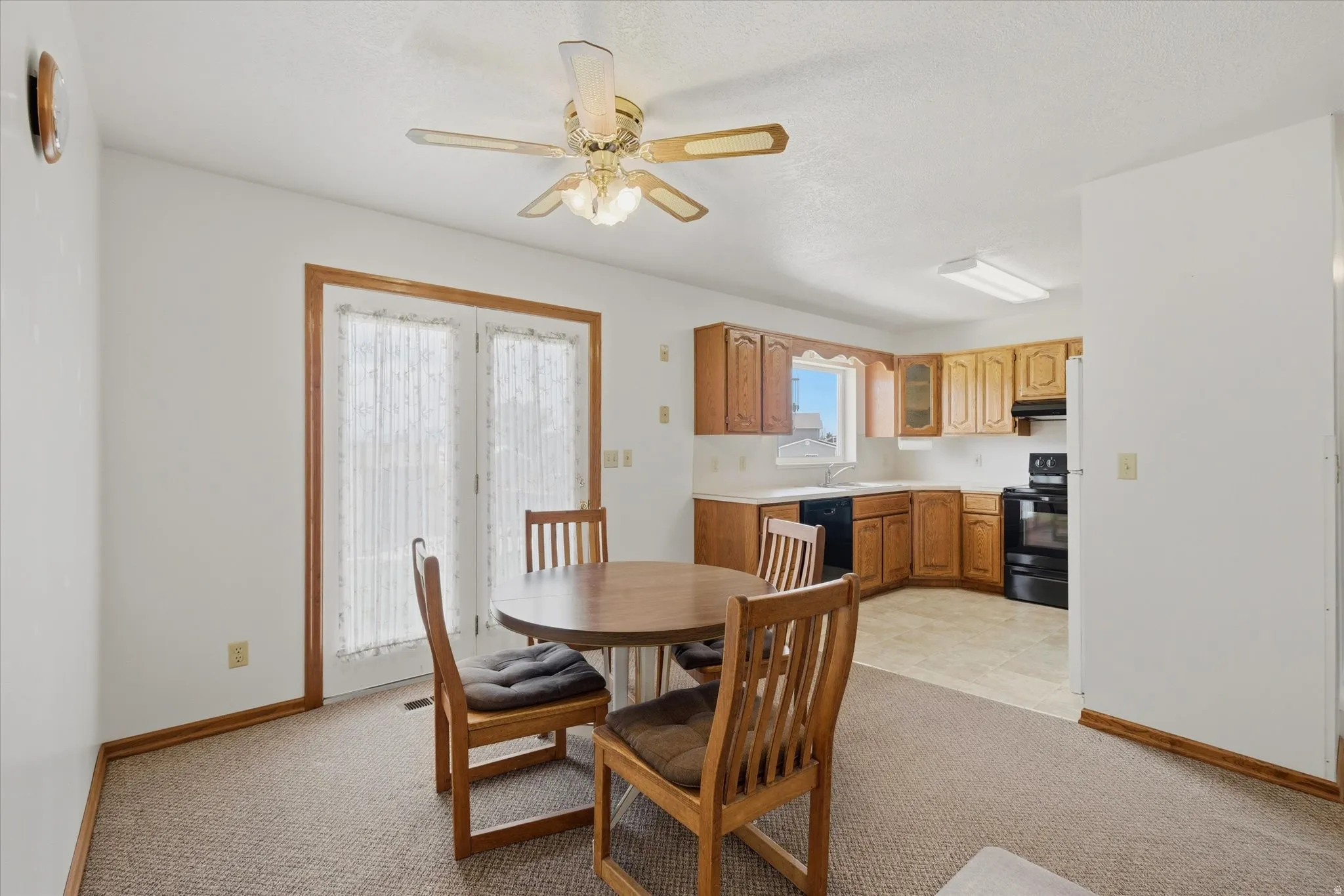 Dining area featuring a ceiling fan with integrated lighting, double patio doors, and carpet flooring