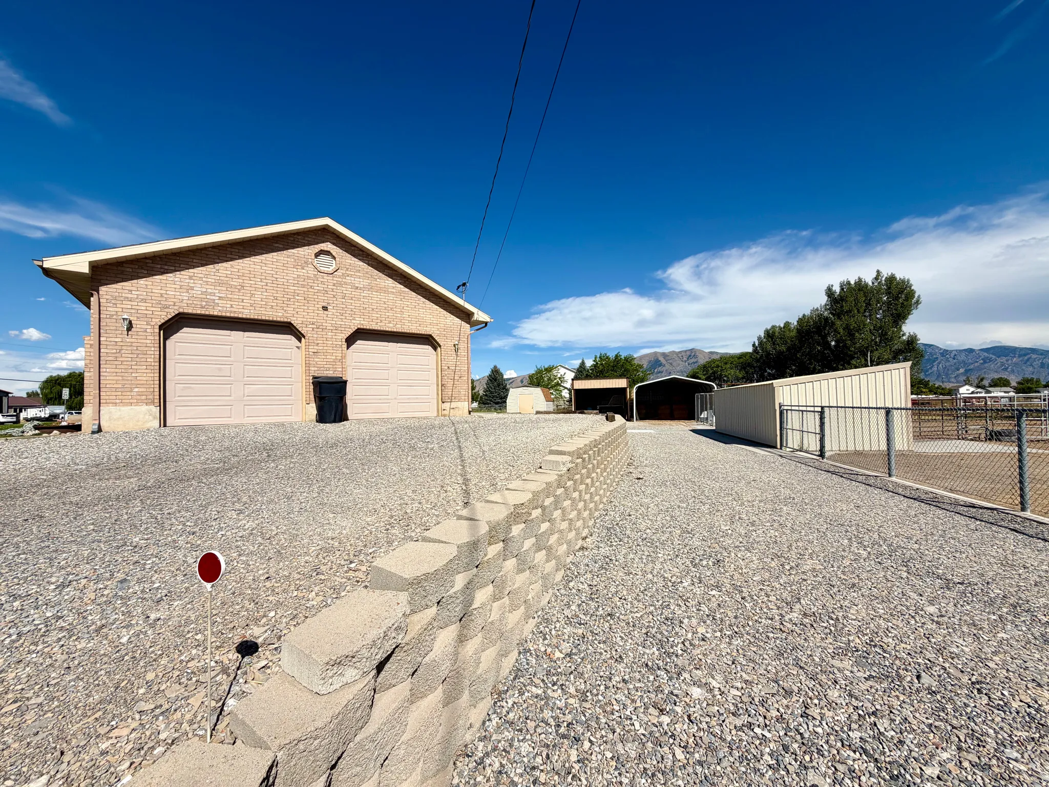 Brick exterior structure featuring two garage bays and a gravel driveway