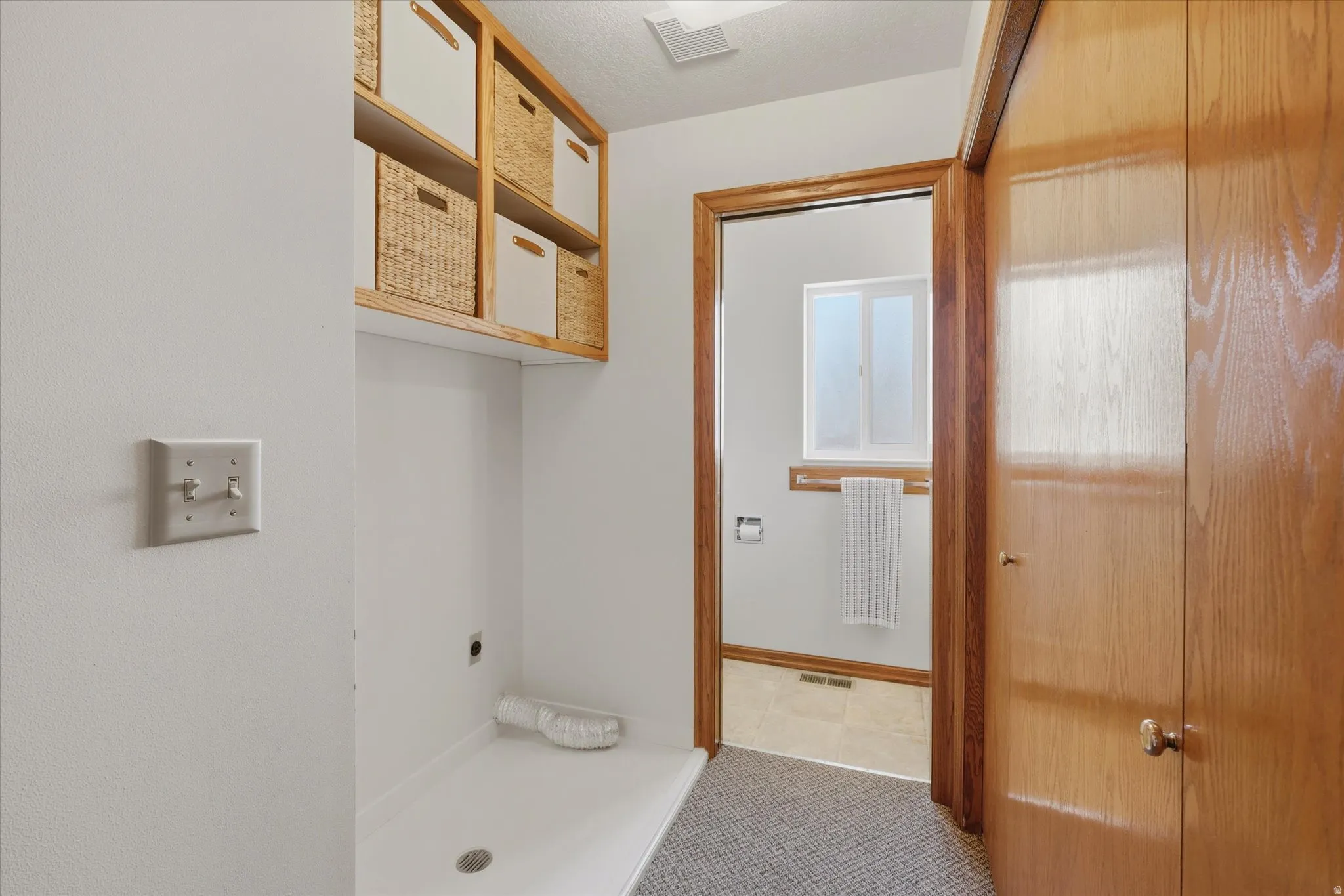 Dedicated laundry area featuring overhead shelving, wood-finish trim, and a utility basin