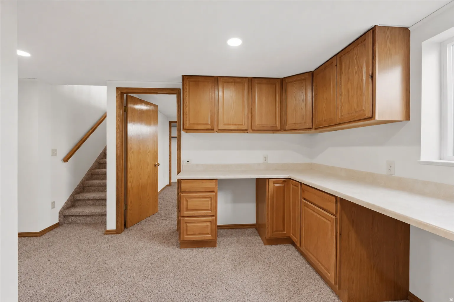 Built-in wood-finish cabinetry, light-toned countertops, and neutral carpeting