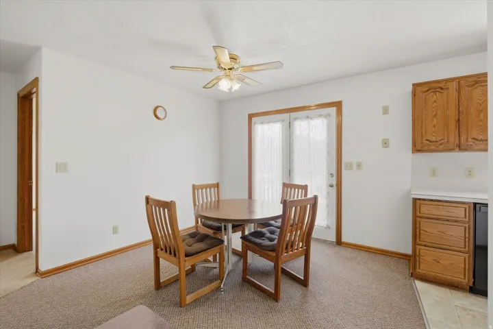 Dining area featuring a ceiling fan with integrated lighting, a doorway with wood trim, and double French doors with sheer curtains