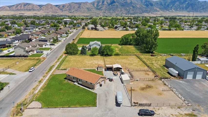 Expansive property featuring a single-story residence, a large detached metal building with multiple bay doors, and several fenced animal enclosures