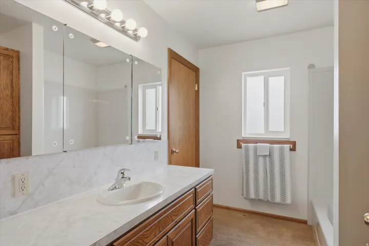 Bathroom featuring a wood-finish vanity with an integrated sink and laminate countertop