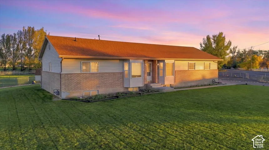 Rambler-style exterior featuring a mix of brick and horizontal siding, a gabled roof, a bay window, and an expansive lawn