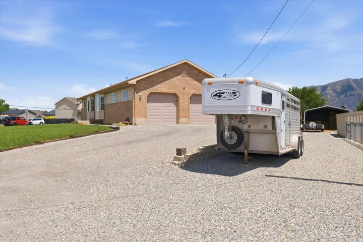 Brick-front property featuring two garage doors, a gravel driveway, and a partially sodded lawn