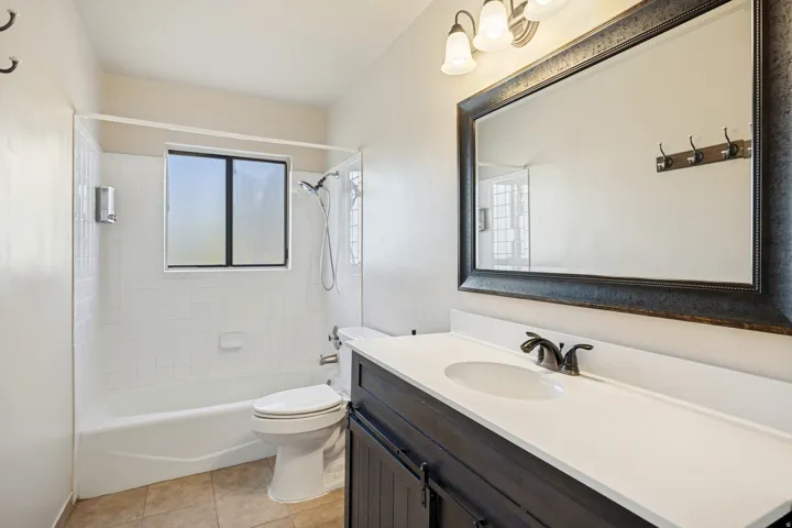 Bathroom featuring a single vanity with a white countertop, dark wood-finish cabinetry, and an oval sink