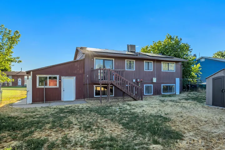 Rear exterior featuring a multi-level structure with brown siding and white trim windows