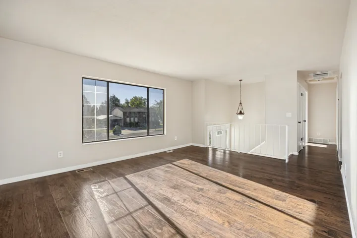 Spacious room featuring wood-finish flooring, a large multi-pane window with black trim, and light-toned wall paint