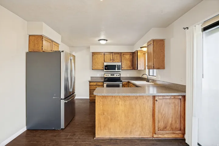 Kitchen featuring wood-finish cabinetry, stainless steel appliances, and wood-finish flooring