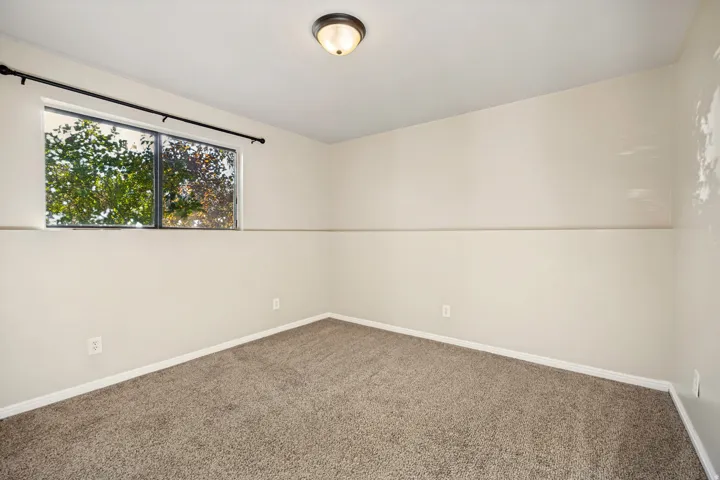 Bedroom featuring a dual-pane window, neutral-toned walls, and plush carpet flooring
