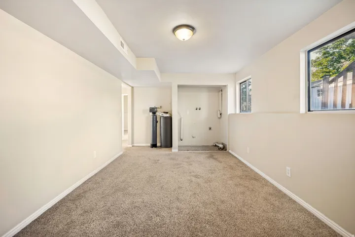 Spacious lower-level room featuring neutral-toned carpeting and light-colored walls