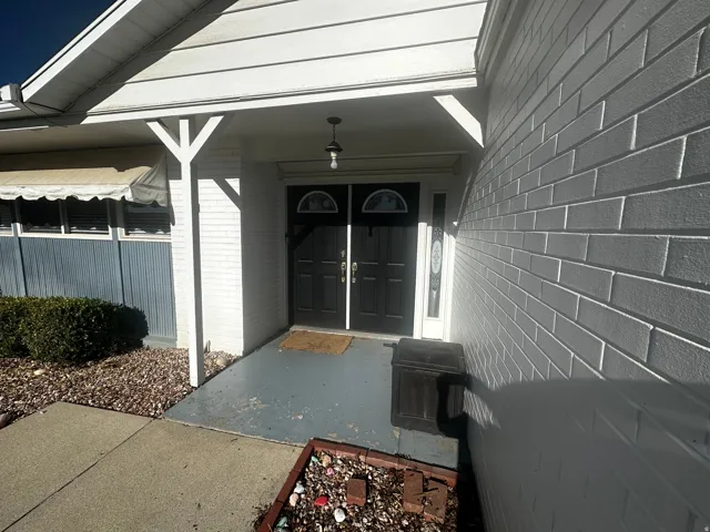 Covered entry featuring a double door entry with sidelights, brick exterior, and a concrete walkway