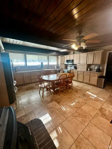 Spacious kitchen featuring extensive neutral cabinetry, a full suite of appliances, and a wood-paneled ceiling with a ceiling fan