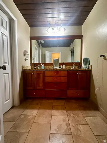 Dual vanity with wood cabinetry and stone-finish countertop