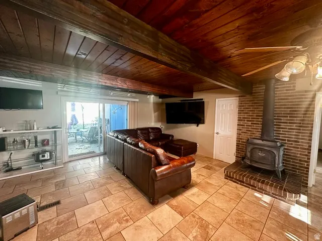 Living space featuring wood-finish ceiling, exposed wood beams, and tile flooring