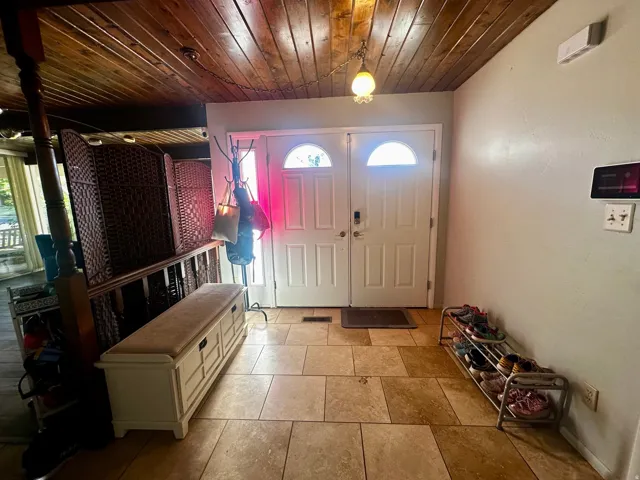 Entryway featuring a wood-panel ceiling, paneled double doors with arched lites, and large format tile flooring