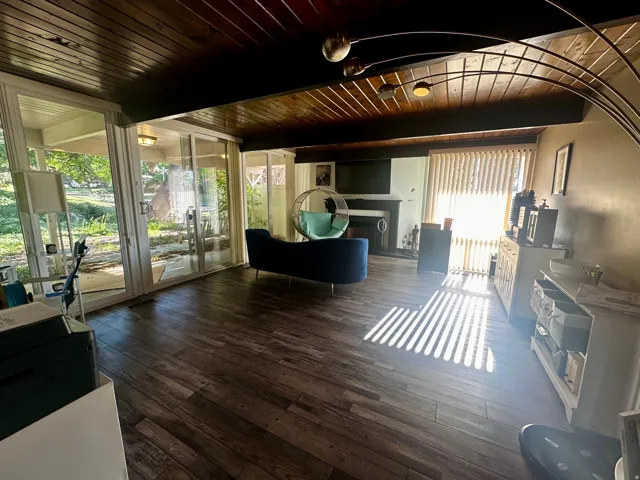 Interior space featuring wood-finish flooring, a wood-paneled ceiling with exposed beams, and a fireplace with a dark mantelpiece