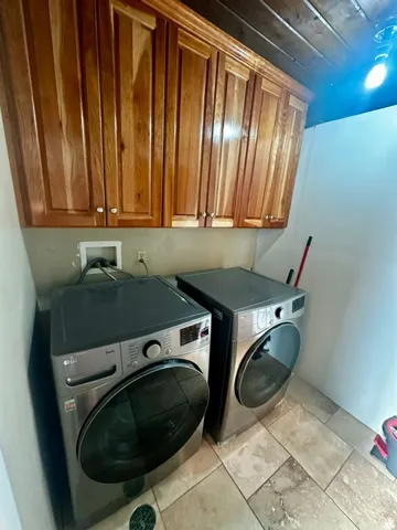 Laundry area featuring wood cabinetry, stone-look tile flooring, and a wood-paneled ceiling