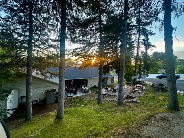 Expansive backyard featuring mature trees, a stone patio, and a dedicated outdoor entertainment area with multiple seating options