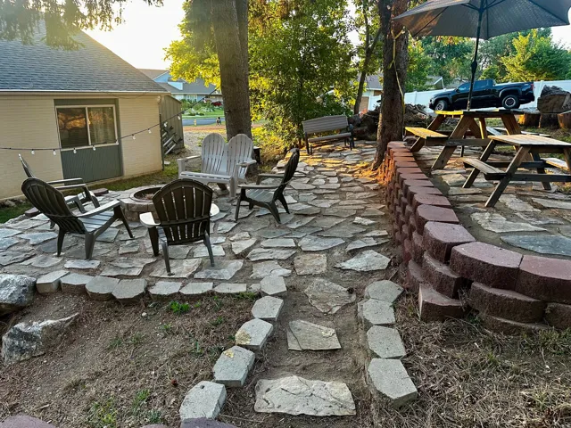 Patio featuring flagstone pavers, a built-in fire pit, and a retaining wall