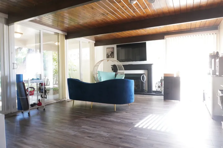 Wood-finish flooring throughout a spacious room featuring a wood-paneled ceiling with exposed beams