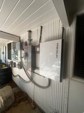 Exterior utility wall featuring a Franklin whole-home battery system and electrical panel