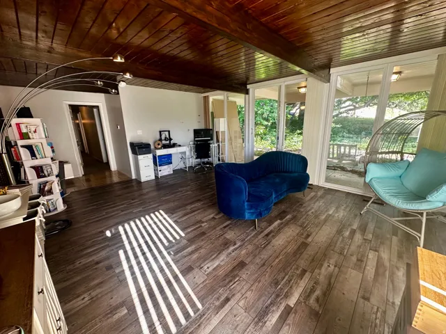Living area featuring wood-finish flooring, a vaulted wood-paneled ceiling, and sliding glass doors to the exterior