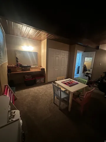 Carpeted room featuring a wood-panel ceiling, built-in shelving, white bi-fold closet doors, and wall-mounted lighting
