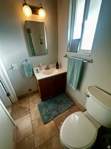 Bathroom featuring a wood vanity with integrated sink, a rectangular mirror, and an overhead two-bulb light fixture