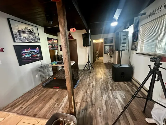 Basement room featuring wood-finish flooring, white walls, and exposed ceiling joists