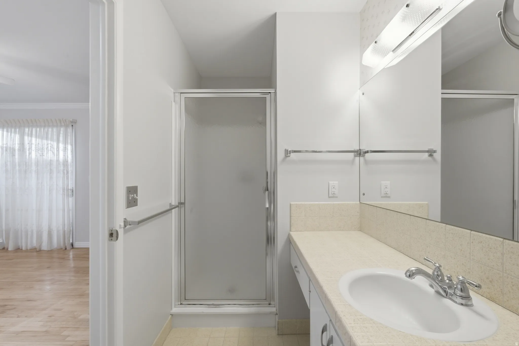 Bathroom featuring an elongated vanity with an integrated sink, chrome faucet, and a large mirror