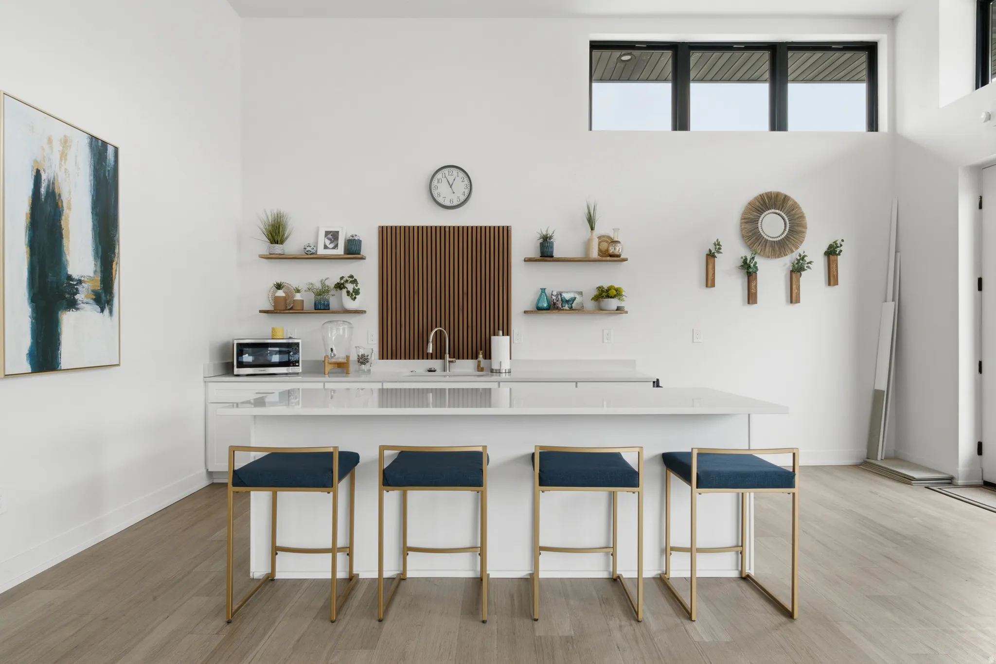 Open-concept kitchen area featuring a central island with countertop seating, wood-finish flooring, a contemporary sink, and built-in shelving