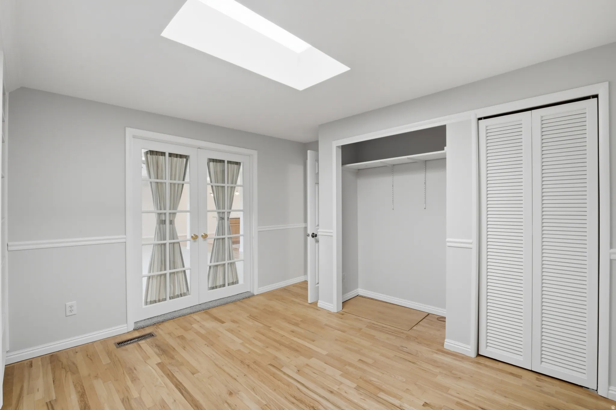 Light wood-finish flooring with white baseboards and chair rail molding