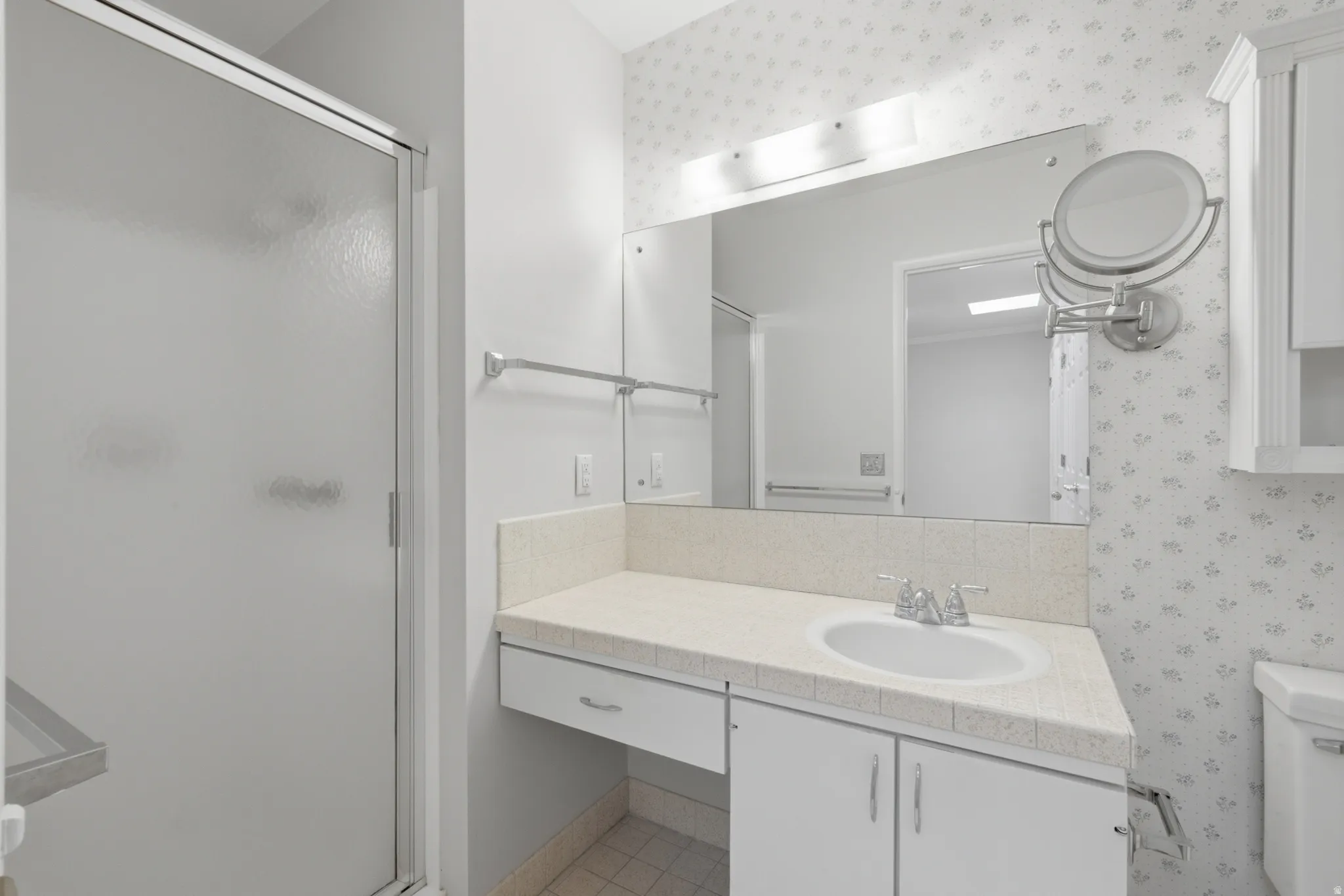 Bathroom featuring a frosted glass shower enclosure and a vanity with a drop-in sink
