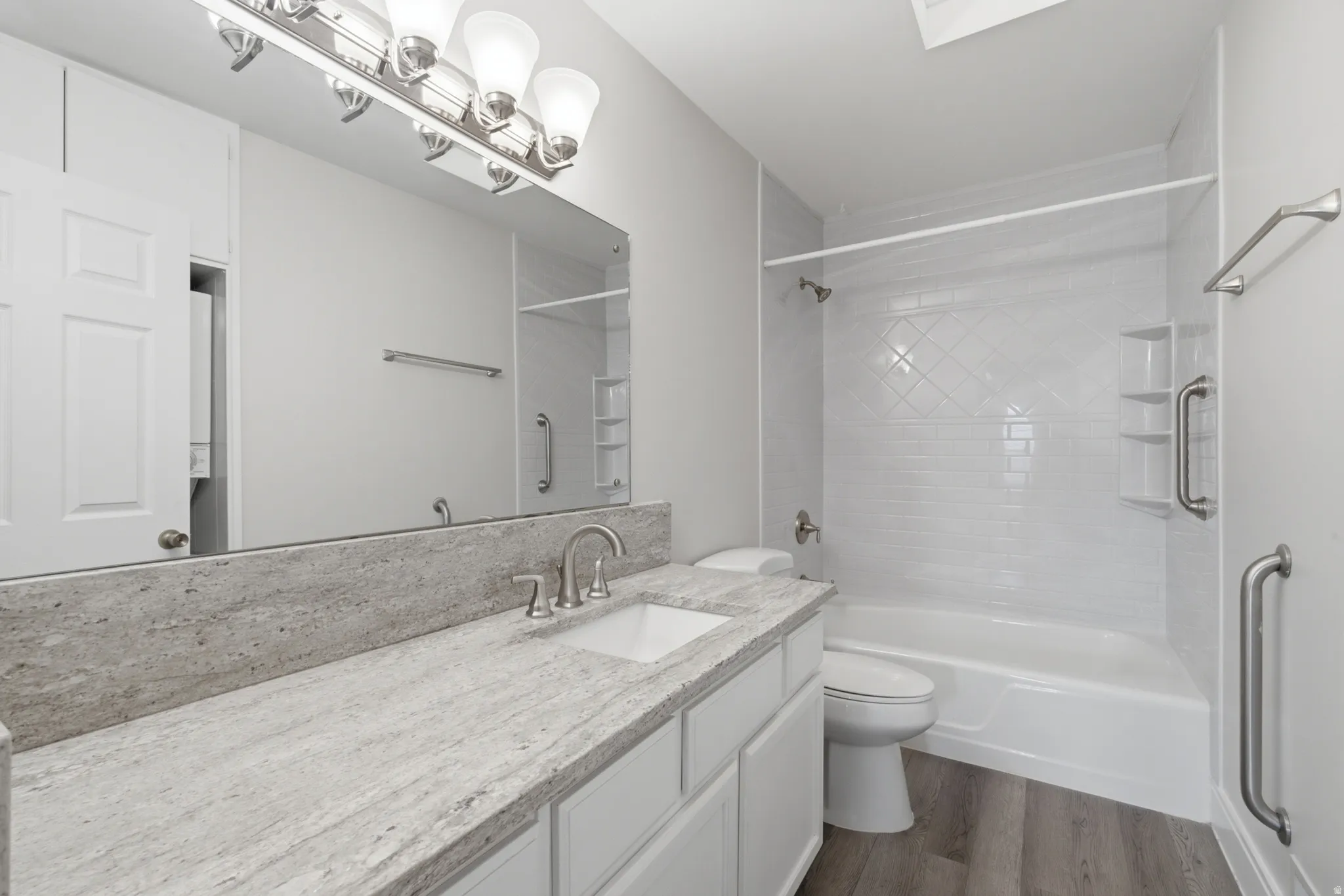Bathroom featuring a white vanity with a stone countertop, an integrated rectangular sink, and a large mirror