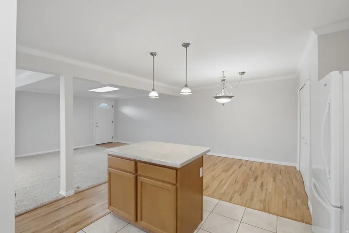 Kitchen island with stone-finish countertop and light wood-finish cabinetry