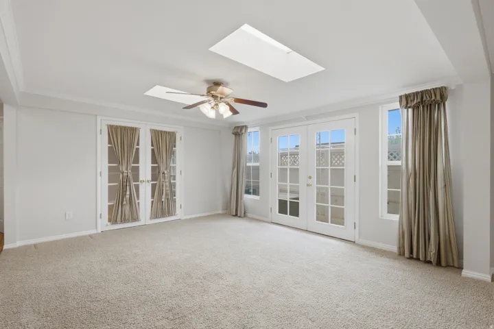 Spacious room featuring light-toned carpeting and multiple sets of French doors