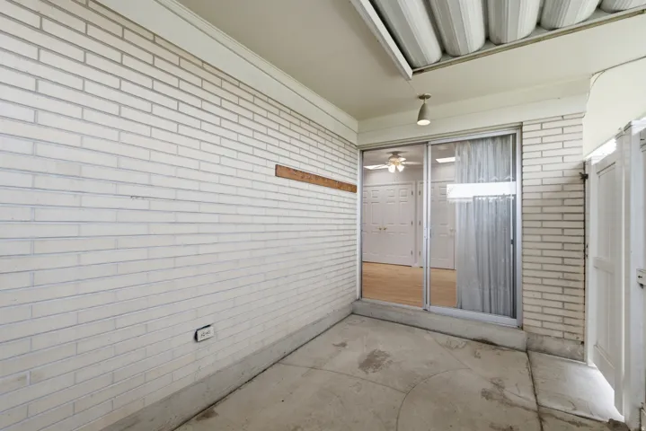 Covered concrete patio with white brick walls