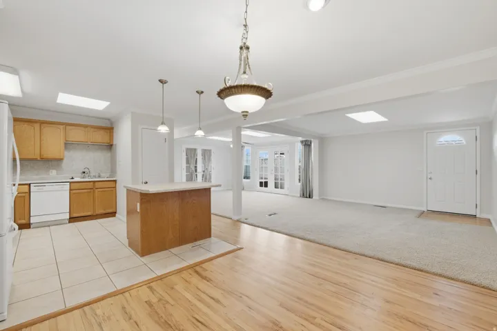 Combined kitchen and living area featuring a kitchen island, recessed lighting, skylights, and French doors