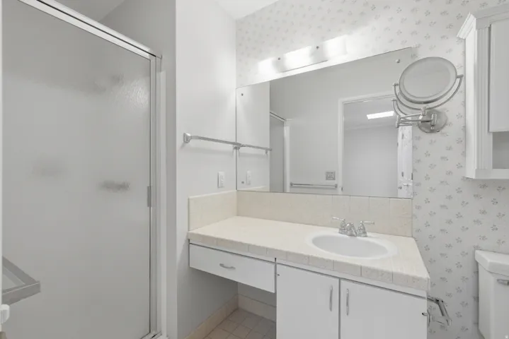 Bathroom featuring a frosted glass shower enclosure and a vanity with a drop-in sink