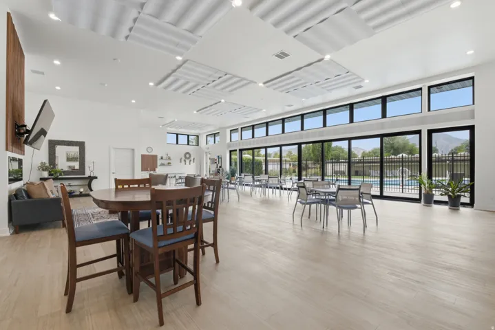 Spacious common area featuring light wood-finish flooring, a contemporary dropped ceiling design, and a full wall of floor-to-ceiling windows