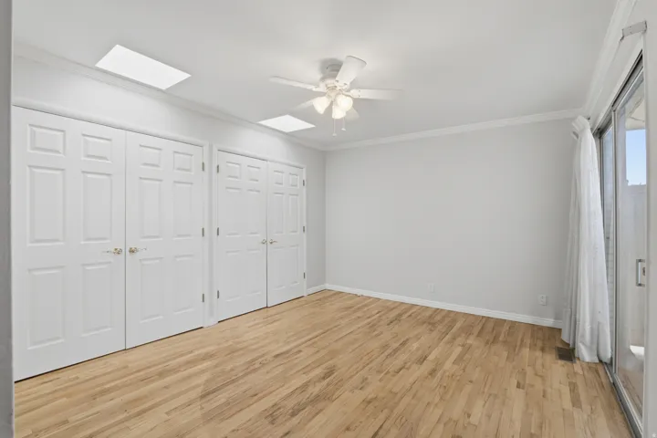 Bright interior space featuring wood-finish flooring, white paneled bifold doors, a ceiling fan, and a sliding glass door